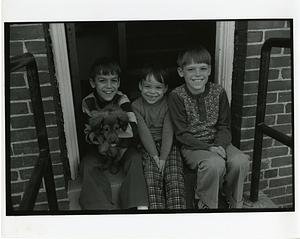 Portrait of three boys and a dog sitting in a doorway