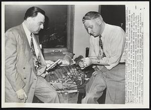 Examine Explosives Found at UAW-CIO Headquarters-- Inspector Joseph V. Krug (left) of the Special Investigation Squad and Inspector Albert Langtry, head of the police Scientific Laboratory, Inspect dynamite and fuses found on a basement stairs of the United Auto Workers International Headquarters building here last night. The dynamite, 39 sticks complete with two detonators and fuses, was found in a corrocated cardboard soap box wrapped in Gaily decorated Christmas paper.