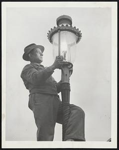 Gaslight Lamplighter Despite the advent of electrically lighted streets 50 years ago, Chicago still maintains 4,400 gas-burning and 260 gasoline street fixtures. Ernest Baggio, who came to the U.S. from Venice, Italy 23 years ago, has attended his particular set of gaslight fixtures since 1926. Here, Joe takes care of one of his lights. He is employed by a company which contracts for the service. The gaslights ignite automatically, but Joe and other employees of the company are required to inspect and to service them.