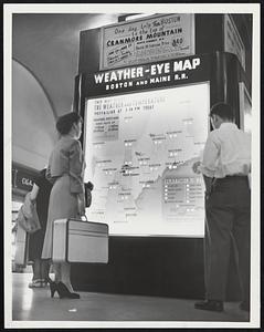 See What You're Getting Into- Mrs. Jean Lusignan, Providence, wife of GI in Korea, checks new North Station weather map before boarding train foe Lawrence. Colored lights tell the weather as far north as Caribou, Me.