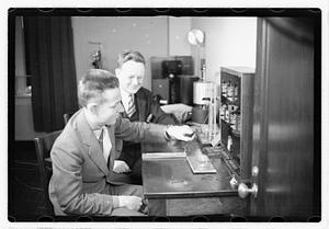 A boy sitting next to a man using an unidentified device