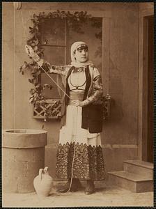 Studio portrait of woman next to well in traditional Greek dress