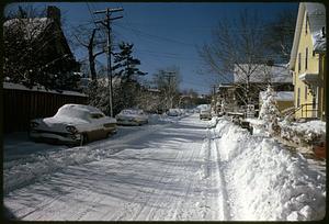 View down residential street with snow on parked cars