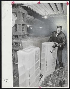 Keeping Cool on hot day is Eddie Mack of South Boston, who has the best job in town today. Eddie, wearing a ski jacket and gloves, pushes large ice blocks onto conveyor belt at Boston Ice Co.