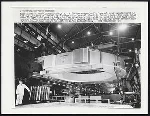 A 56-ton magnet coil, largest ever manufactured in the U.S., is gently lowered by a crane at a General Electric factory here. Two such coils were shipped this week by barge to Virginia, where they will be used in a new NASA atom-smasher. When completed, the atom-smasher's magnet will have a pulling power greater than 3,500 tons-- strong enough to lift 30 large locomotives.