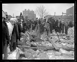 A group of people gathered by rubble trying to rescue an animal