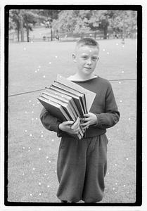A boy holding a stack of books