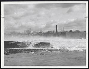 Water of the flood-swollen Connecticut River rushes over the Holyoke Dam in Holyoke today. The high water has caused the closing of several paper mills in the city.