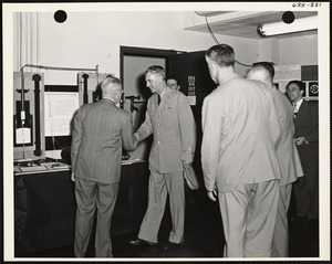 Officers and men at exhibit, shaking hands