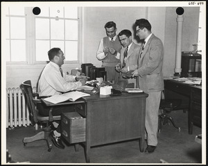 Men with objects at desk