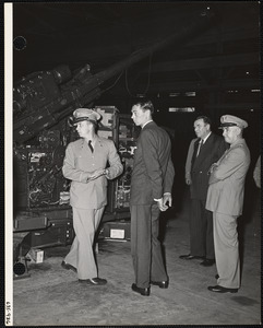 Men and military officers inspecting ordnance