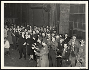 Spectators cheering at announcement of completion of pouring for 100,000th centrifgual cast gun barrel during army hour broadcast, 20 February 1944, from foundry of Watertown Arsenal, Watertown, Massachusetts