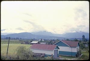 Farm buildings and fields with hills in background, British Columbia