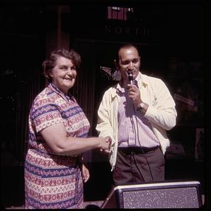 A woman shaking the hand of a man holding a microphone