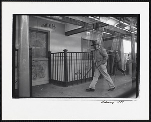 Photograph of man walking taken from inside an Orange Line train