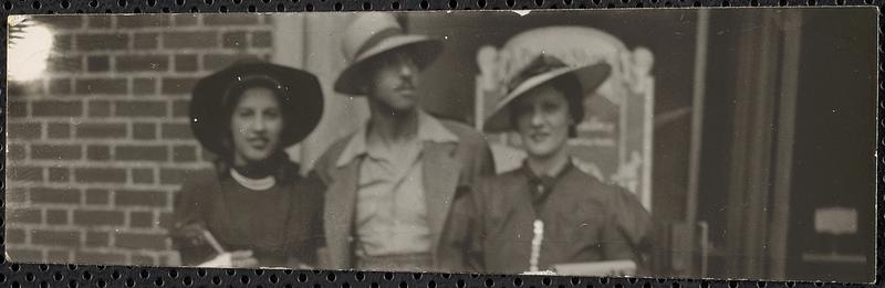 Two women and a man stand in front of a storefront