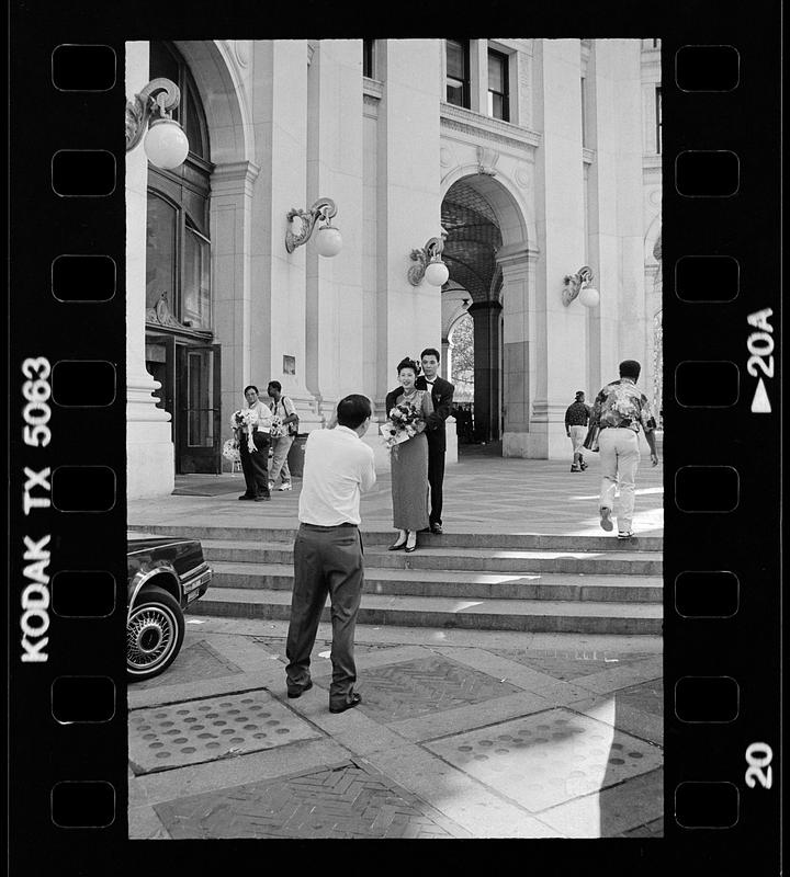 Formally dressed couple being photographed, possibly after a civil wedding