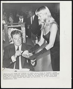Flynn and Protege at Party--Errol Flynn is handed a plate of food by this protege, Beverly Aadland, at a Hollywood party in September 1958. The 17-year-old blonde was with the 50-year-old matinee idol when he died of a heart attack last night in Vancouver, B. C.