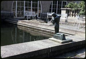 Sculpture of penguins and a kneeling figure next to water