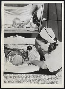 Infant Polio Victim--Tiny Dianne Chabot, 4 1/2 month baby daughter of Mr. and Mrs. Albert Chabot, lies completely paralyzed in an iron lung at the county hospital here where she is said to be the youngest polio victim ever confined at that institution. Nurse Winifred Wagg adjusts a tube administering oxygen to the baby, with every effort being made since her confinement last Tuesday, to keep the tiny sparkle of life alive.