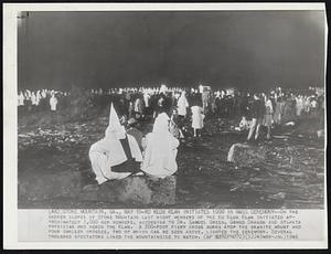 Ku Klux Klan Initiates 1000 in Mass Ceremony--On the barren slopes of Stone Mountain last night members of the Ku Klux Klan initiated approximately 1,000 new members, according to Dr. Samuel Green, Grand Dragon and Atlanta physician who heads the Klan. A 300-foot fiery cross burns atop the granite mount and four smaller crosses, two of which can be seen above, lighted the ceremony. Several thousand spectators lined the mountainside to watch.