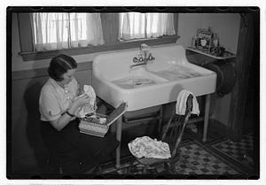 A woman sewing next to a sink full of laundry
