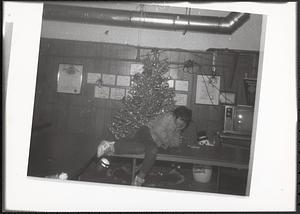 Young person sitting on a table in front of a Christmas tree