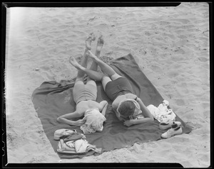 Two girls sunbathing at the beach