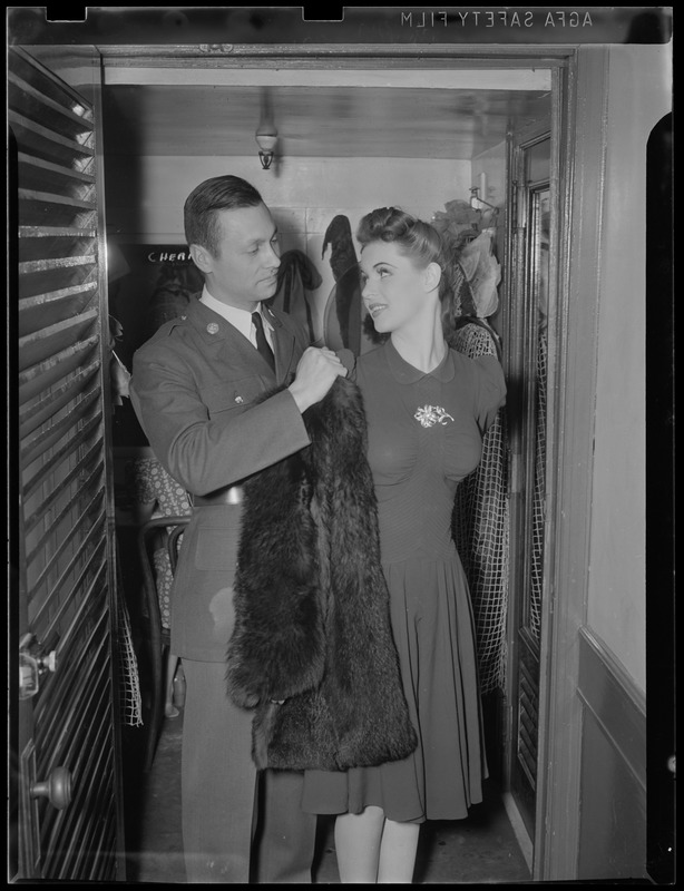 Soldier helps girl on with coat in dressing room