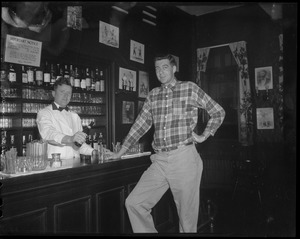 Bartender pours tall beer for tall man at bar with shark jaw