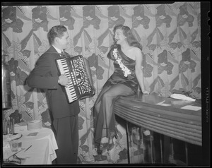 Man plays accordion for woman at bar