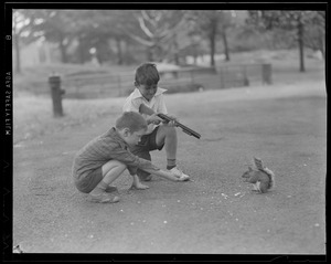 Two boys, one with toy gun, aiming at a squirrel