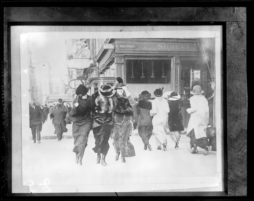 Stylish belles in floppy hats and long velvet skirts on a windy day, corner of Tremont & West Streets