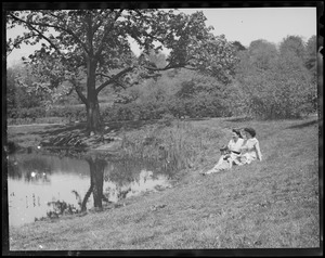 Women & children seated next to pond