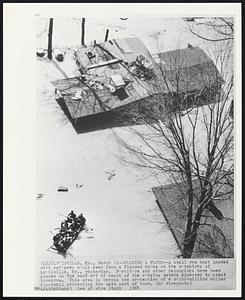 Fleeing a Flood--A small row boat loaded with refugees pulls away from a flooded house on the outskirts of Louisville, Ky., yesterday. Furniture and other belongings have been placed on the roof out of reach of the surging waters expected to crest tomorrow. This area is beyond the protection of a multi-million dollar floodwall protecting the main part of town.
