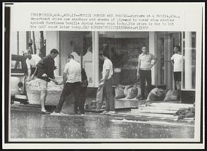 Mobile Boards and Braces--Workers at Mobile, Ala., department store use sandbags and sheets of plywood to cover show windows against Hurricane Camille during heavy rains today. The storm is due to hit the Gulf coast later today.