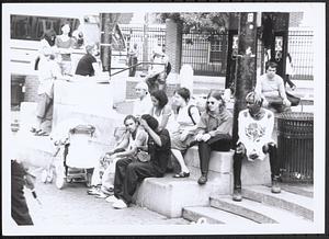 Group of people sitting outside by the Harvard Square T station
