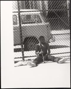 Erel sitting against a chain-link fence