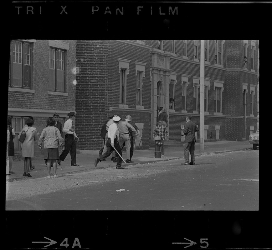 Police officers and others on sidewalk, most likely near Jeremiah E. Burke High School in Dorchester after unrest broke out during student demonstrations