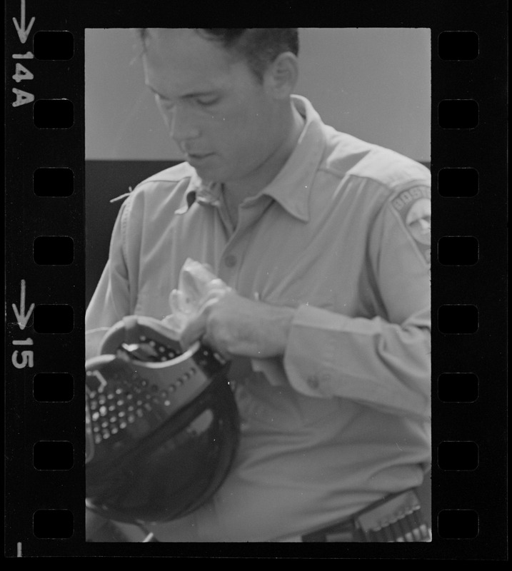 Policeman holding helmet, most likely near Jeremiah E. Burke High School after unrest broke out during student demonstrations