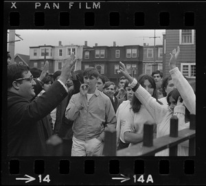 Unidentified man and students raising hands while standing by gate of East Boston High School during demonstrations