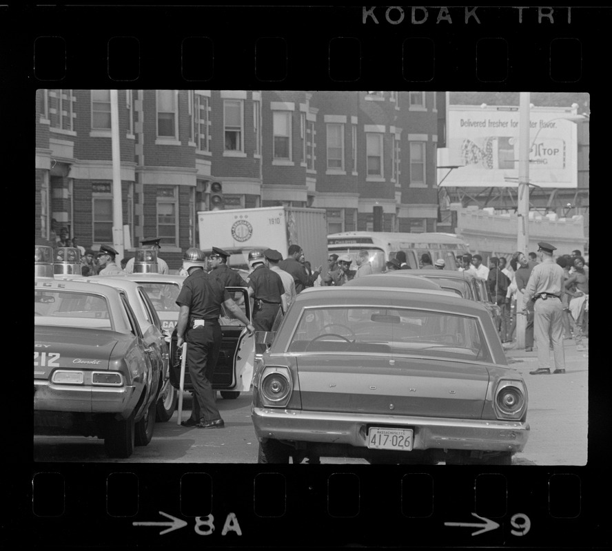 Riot police standing among cars and crowds on Washington Street near Jeremiah E. Burke High School after unrest broke out during student demonstrations