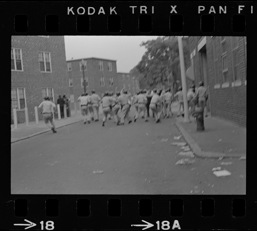 Riot police in the middle of a street and seen from behind, most likely in Roxbury  after unrest broke out during student demonstrations