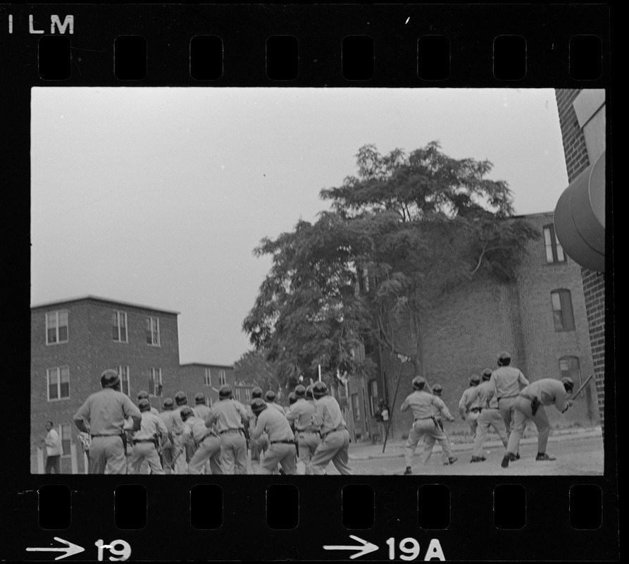 Riot police in the middle of a street and seen from behind, most likely in Roxbury  after unrest broke out during student demonstrations