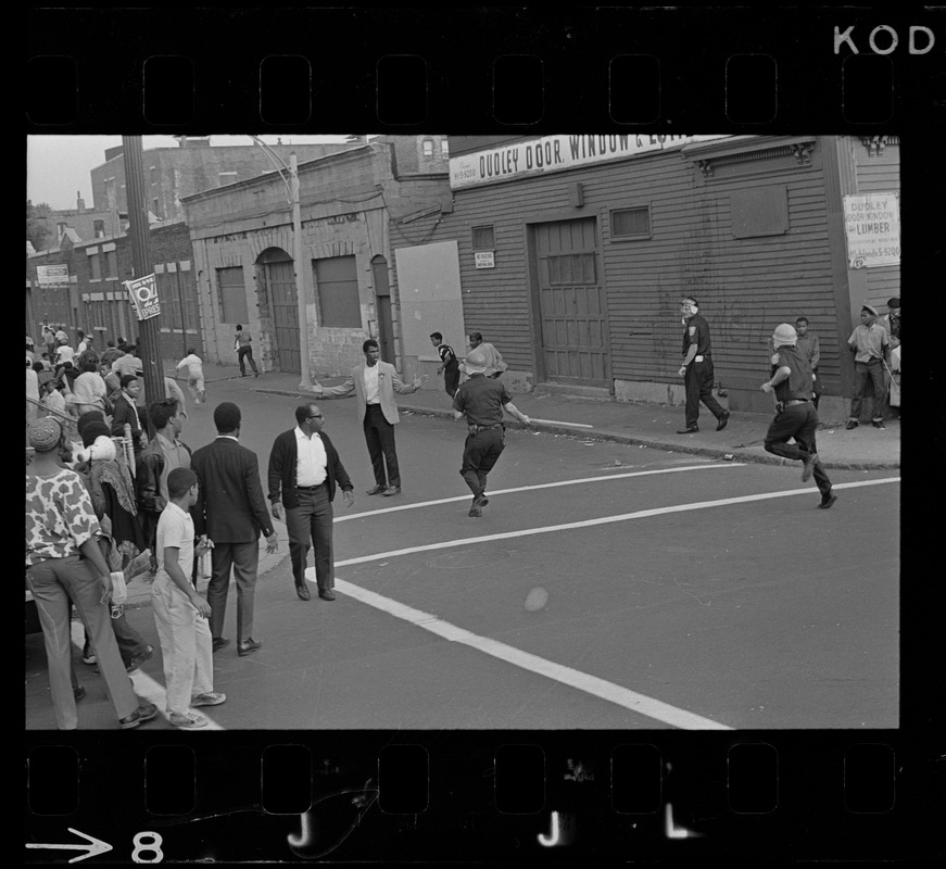 Riot police in the middle of a Roxbury street, possibly in pursuit of suspects,  after unrest broke out during student demonstrations at nearby high schools