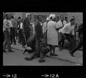 Person on ground surrounded by people and officers, most likely in Roxbury during the time of student demonstrations