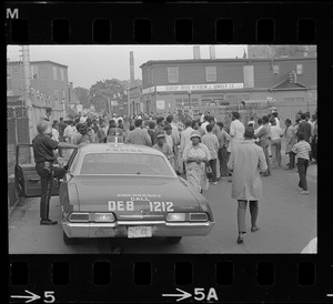 Crowds in the street most likely near car that was set afire in Roxbury during time of student demonstrations
