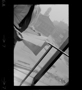 Mayor White standing by a window in his City Hall office overlooking Faneuil Hall and reviewing papers