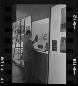 Unidentified man holding a small bust of John F. Kennedy Jr. while standing in front of an exhibit case