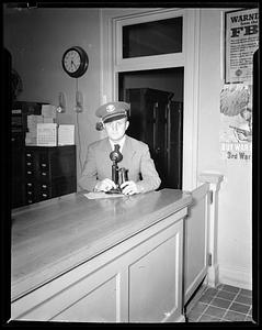 Man in military uniform standing at counter with a telephone